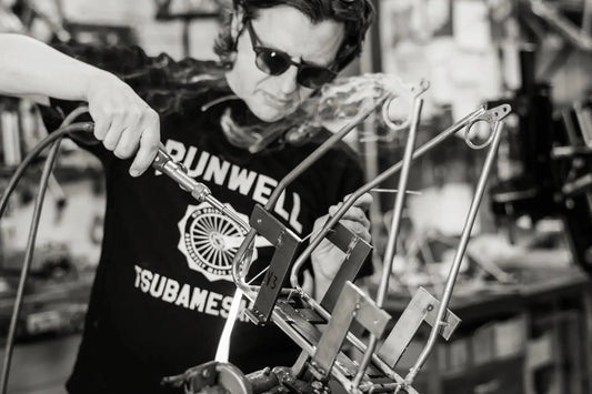 Von Hand werden die Gepäckträger nach dem Biegen der Rohre mit Messing verlötet